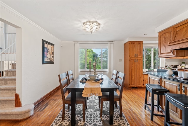 dining room with ornamental molding and light hardwood / wood-style floors