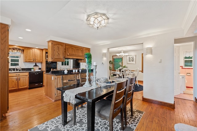 dining space featuring an inviting chandelier, light hardwood / wood-style floors, ornamental molding, and sink