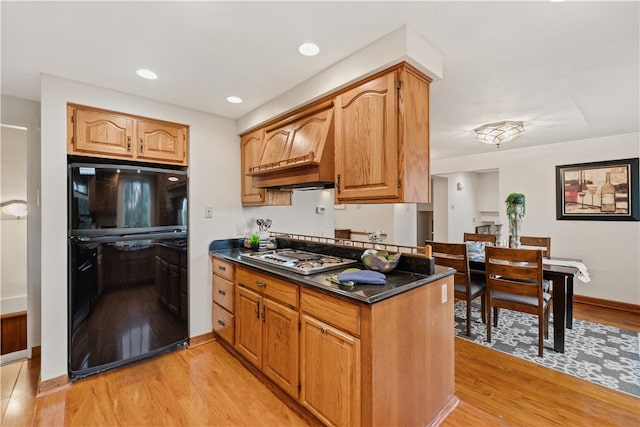 kitchen featuring custom exhaust hood, light wood-type flooring, black double oven, and stainless steel gas cooktop