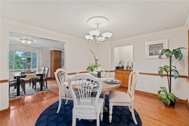 dining space with ornamental molding, an inviting chandelier, and light hardwood / wood-style floors