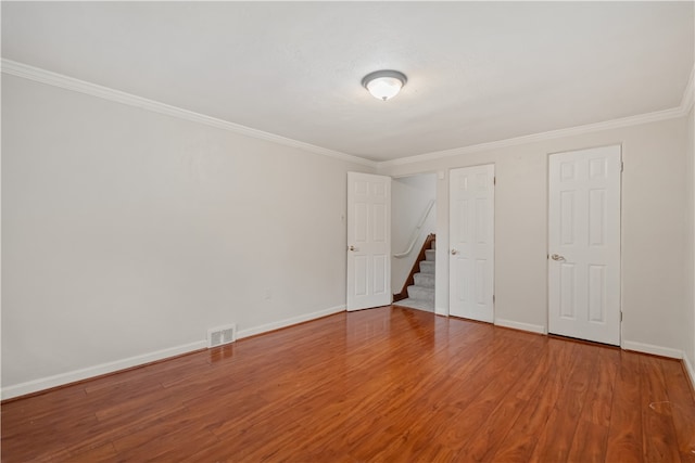 empty room featuring ornamental molding and hardwood / wood-style floors