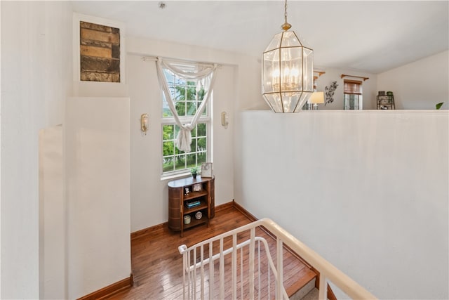 staircase featuring an inviting chandelier and wood-type flooring