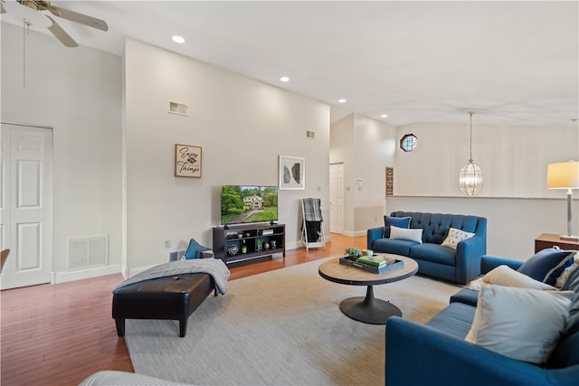 living room with high vaulted ceiling, ceiling fan with notable chandelier, and hardwood / wood-style floors