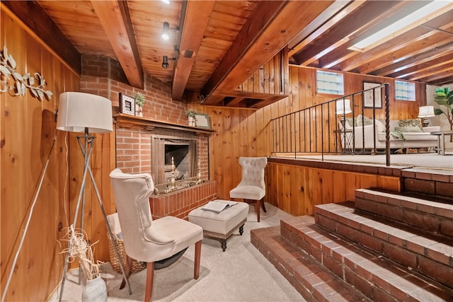 sitting room with wooden walls, beam ceiling, a fireplace, and carpet flooring