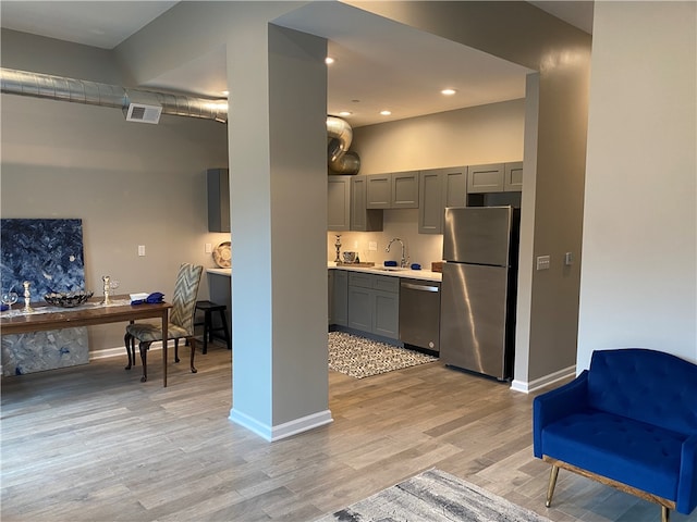 kitchen with light hardwood / wood-style floors, stainless steel appliances, sink, and gray cabinets