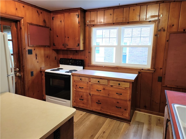 kitchen featuring light wood-type flooring, white appliances, wood walls, and sink