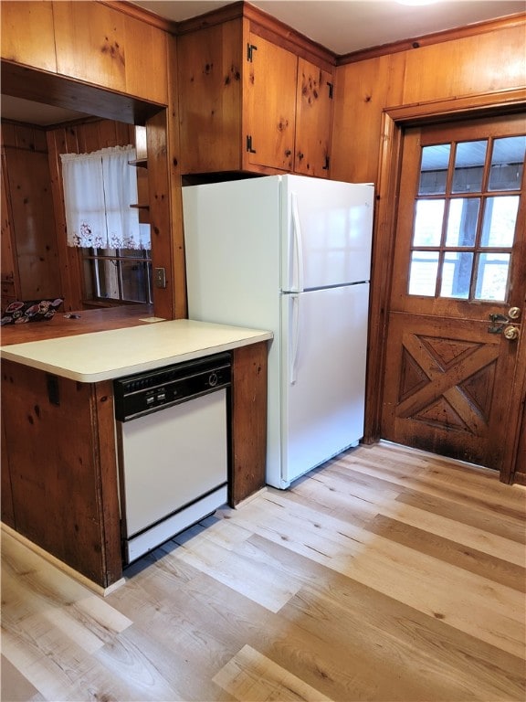 kitchen featuring white appliances, light hardwood / wood-style floors, and wood walls