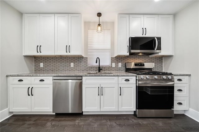 kitchen featuring white cabinets, appliances with stainless steel finishes, hanging light fixtures, and sink