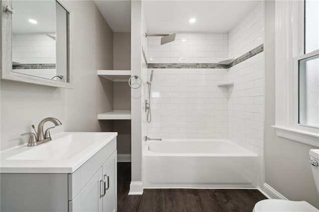 full bathroom featuring hardwood / wood-style floors, tiled shower / bath combo, vanity, and toilet