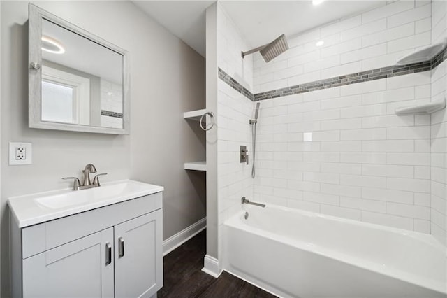 bathroom featuring wood-type flooring, vanity, and tiled shower / bath