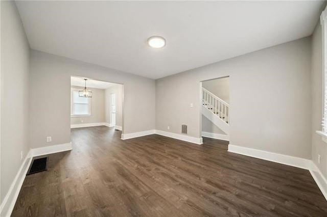 unfurnished room with a notable chandelier and dark hardwood / wood-style flooring