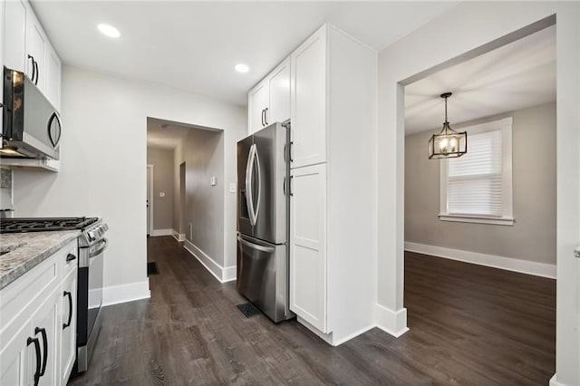 kitchen featuring light stone counters, white cabinets, decorative light fixtures, dark wood-type flooring, and appliances with stainless steel finishes