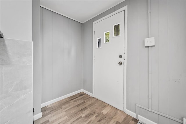 doorway with light hardwood / wood-style flooring and wooden walls