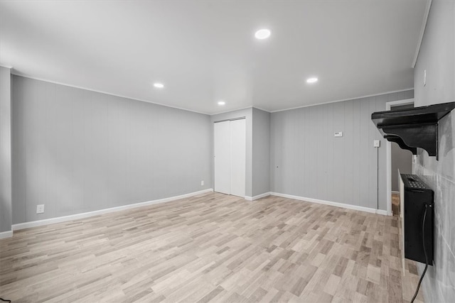 unfurnished living room featuring light hardwood / wood-style flooring, a fireplace, and wood walls