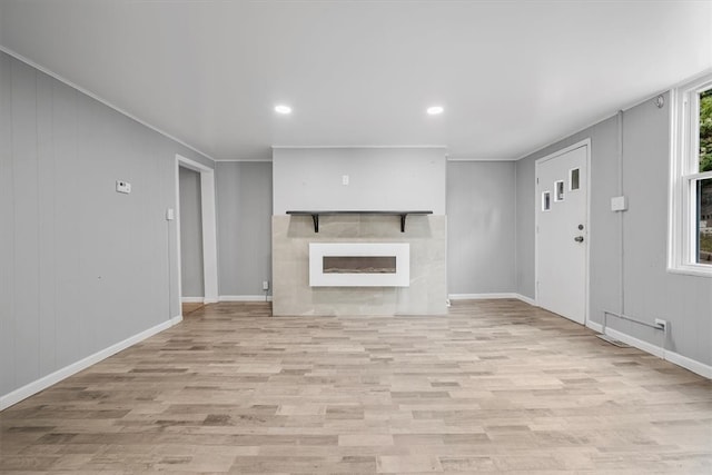 unfurnished living room featuring light wood-type flooring, crown molding, and a fireplace