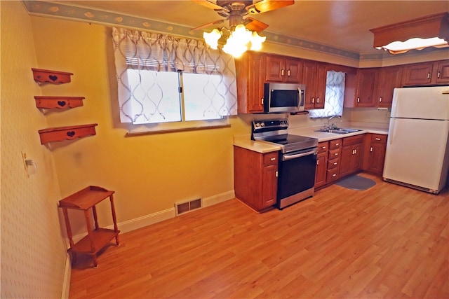 kitchen featuring a wealth of natural light, sink, stainless steel appliances, and light hardwood / wood-style floors