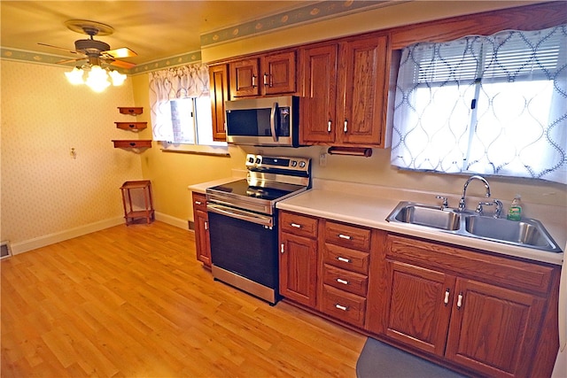 kitchen featuring ceiling fan, sink, stainless steel appliances, and light hardwood / wood-style floors