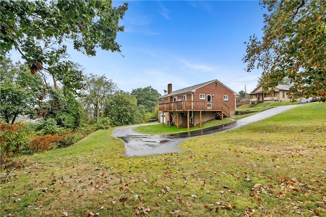 rear view of house featuring a lawn and a deck