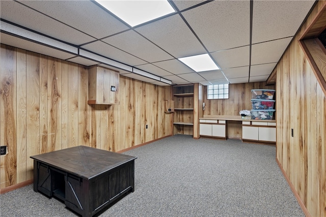 basement with wood walls, a paneled ceiling, and carpet flooring