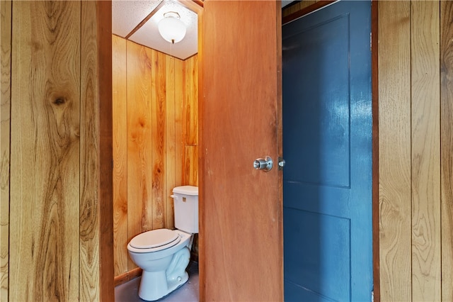 bathroom with toilet and wood walls