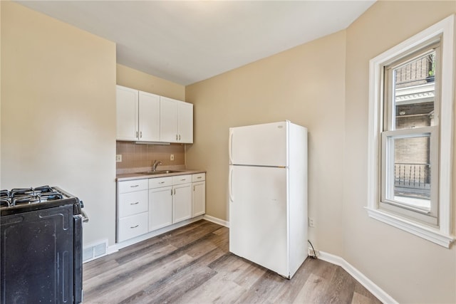 kitchen featuring light hardwood / wood-style flooring, white cabinets, white refrigerator, and sink