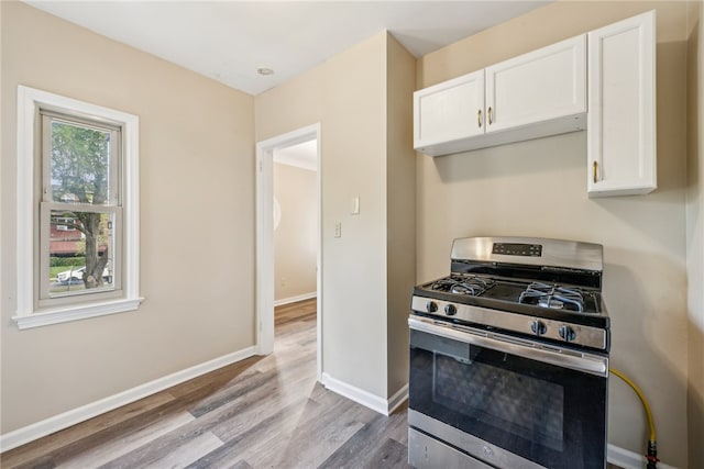 kitchen featuring stainless steel gas range oven, light wood-type flooring, and white cabinetry