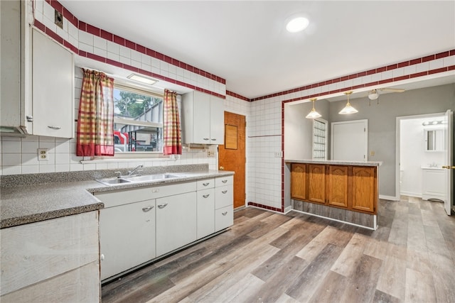 kitchen featuring light hardwood / wood-style flooring, sink, pendant lighting, and white cabinets