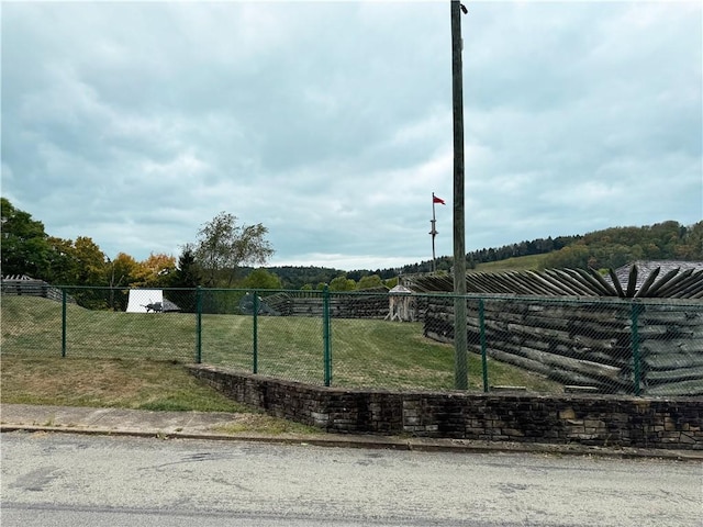 view of home's community featuring a rural view, fence, and a lawn