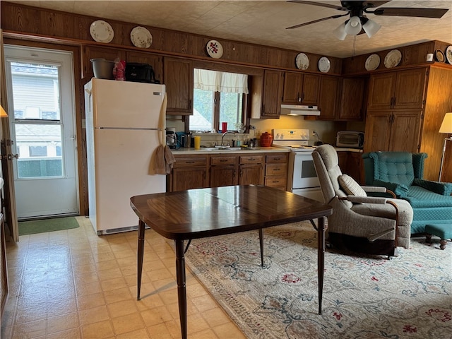 kitchen with sink, white appliances, ceiling fan, and wood walls