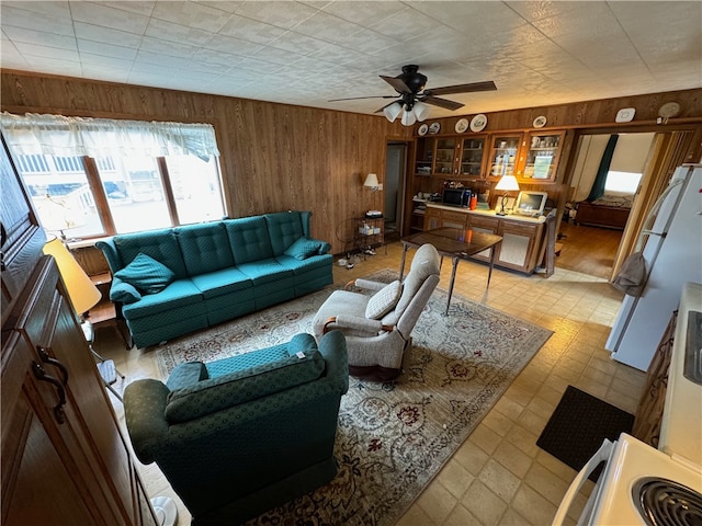 living room with ceiling fan and wood walls