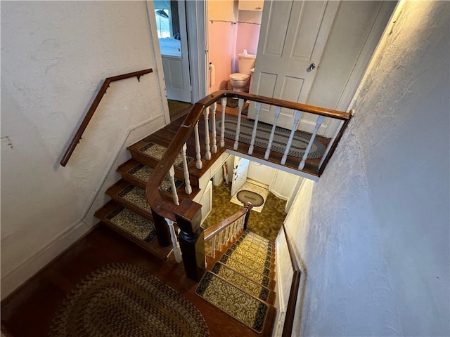 stairway featuring wood finished floors and a textured wall
