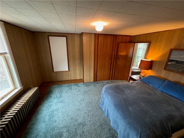 bedroom with carpet flooring, wooden walls, and radiator