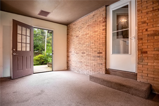 interior space with brick wall and a textured ceiling