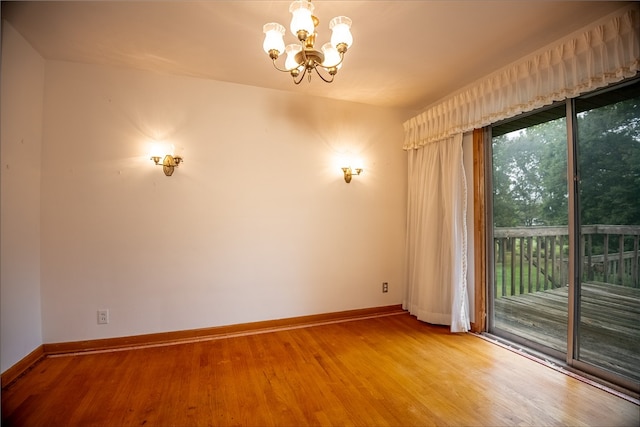 spare room featuring a notable chandelier and wood-type flooring