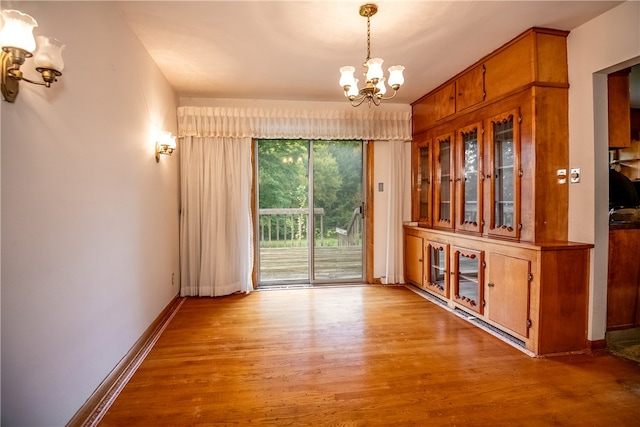 unfurnished dining area with a notable chandelier and light hardwood / wood-style flooring