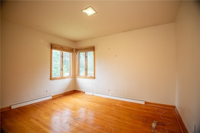 unfurnished room featuring wood-type flooring and baseboard heating