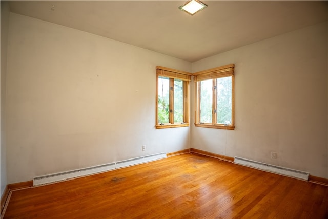 unfurnished room featuring light wood-type flooring and a baseboard heating unit