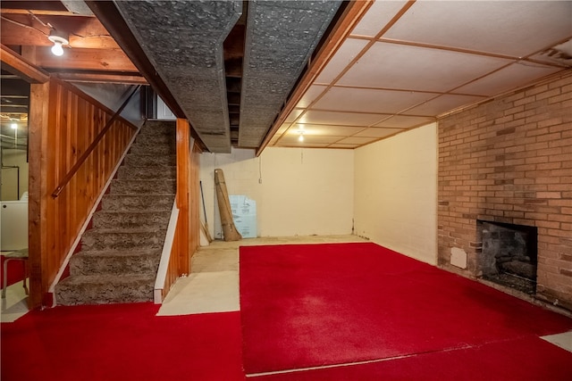 basement featuring a brick fireplace, carpet floors, and brick wall