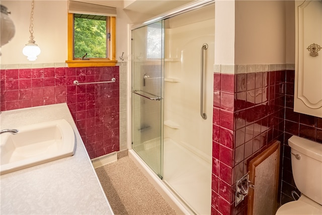 bathroom with tile walls, a shower with door, vanity, and toilet