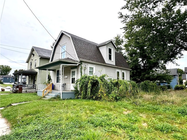 view of side of home featuring covered porch and a yard