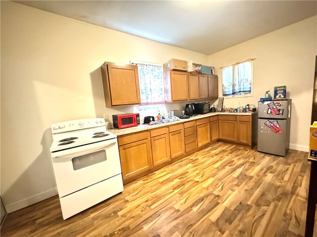 kitchen with stainless steel refrigerator, light hardwood / wood-style floors, white range with electric stovetop, and a wealth of natural light