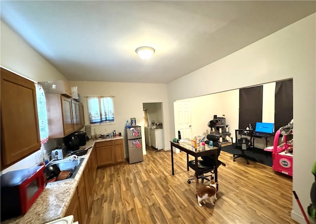 kitchen featuring stainless steel fridge, independent washer and dryer, lofted ceiling, light hardwood / wood-style flooring, and sink