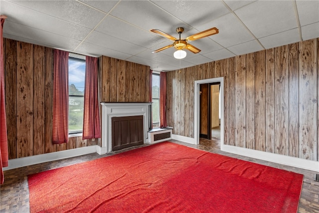 unfurnished living room with ceiling fan, a paneled ceiling, and a wealth of natural light