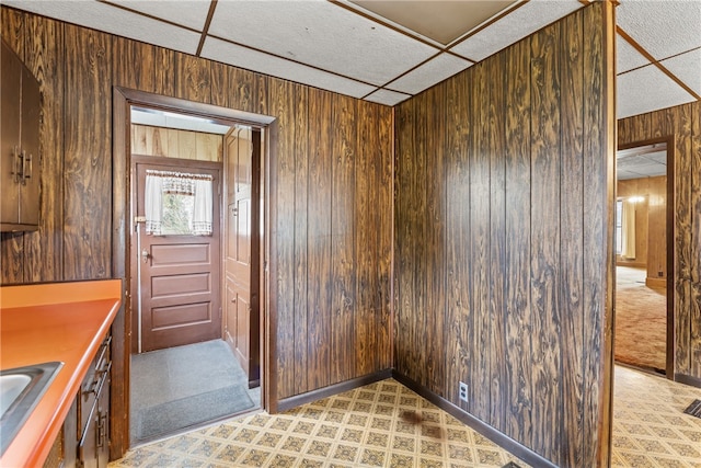 interior space with a paneled ceiling, wooden walls, and sink