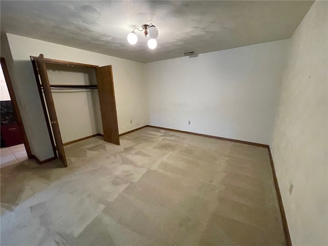 unfurnished bedroom featuring light carpet and a closet