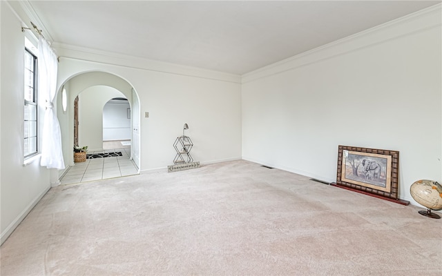 unfurnished living room with ornamental molding, light colored carpet, and a wealth of natural light