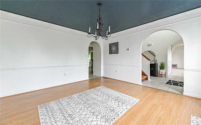 unfurnished room featuring wood-type flooring and an inviting chandelier