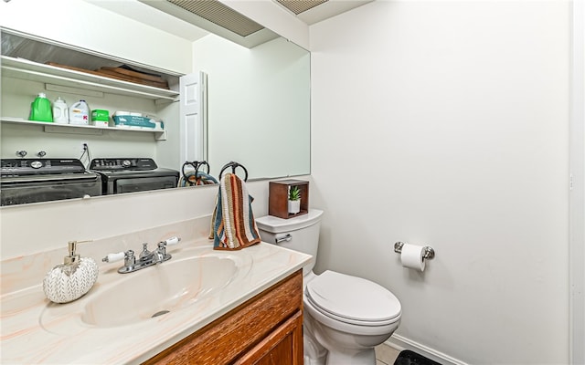 bathroom featuring tile patterned flooring, vanity, toilet, and washing machine and clothes dryer