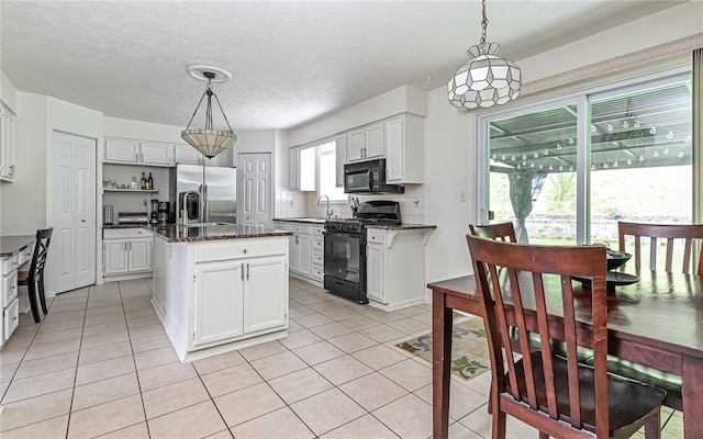 kitchen with black appliances, hanging light fixtures, white cabinetry, and a center island