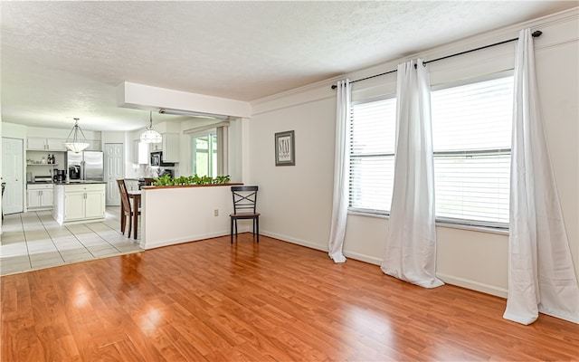 unfurnished living room featuring a textured ceiling and light hardwood / wood-style floors